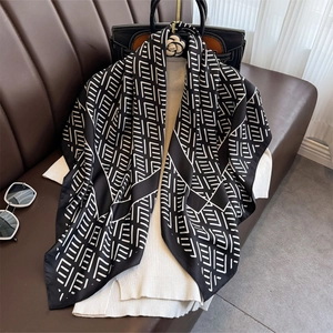 Elegant black and white striped silk square scarf styled with a knit sweater on a leather sofa