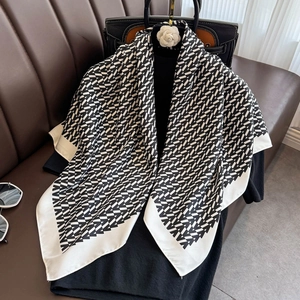 Elegant silk scarf featuring black and white V-pattern with white border on a classic outfit