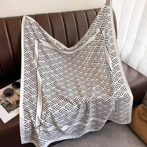 Detail of striped silk twill scarf draped over leather sofa with fashion accessories