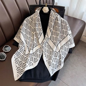 Elegant black and white geometric silk scarf draped over an outfit on a leather sofa