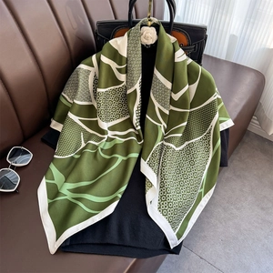 Green and white floral print silk square scarf styled on a luxury handbag and leather sofa