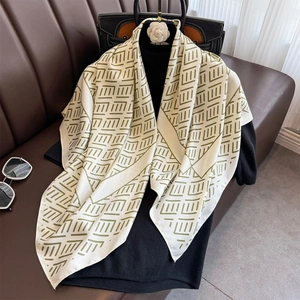 Detail of silk-feel scarf featuring green geometric patterns on a beige square wrap