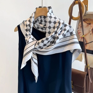 Detail eines bedruckten Seidenschals auf blauem Kleid mit geometrischen Mäander-Mustern