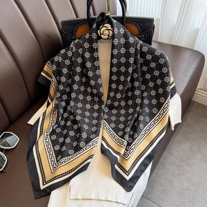 Eleganter 90cm Seidenschal in Schwarz und Gold mit Mäander-Muster über einem Pullover