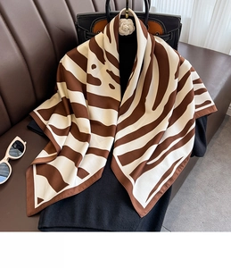 Detailed texture of brown zebra print silk scarf draped over a black top and leather sofa