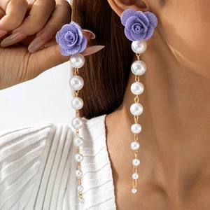 Detail of purple fabric rose earring with gradient pearls and elegant gold chain tassel
