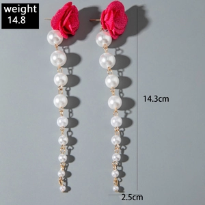 Detail view of red fabric rose earrings with long white pearl tassels and golden alloy chain