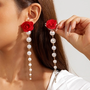 Close-up of dangling earrings with red fabric rose and gradient pearl tassel detail