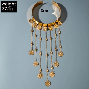 Détail d'un brassard doré style western avec franges métalliques, perles et sequins