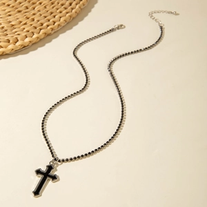 Détail du pendentif croix noire évidée avec bordure argentée et chaîne à strass noirs