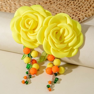 Detail of yellow camellia earrings with vibrant beaded fringe and green leaf accents