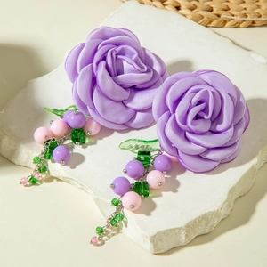 Detail of handmade purple satin rose earrings with colorful beads and crystal charms