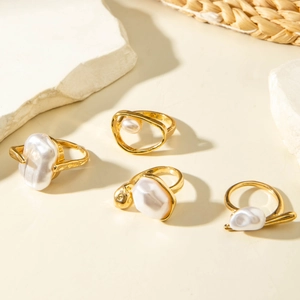 French retro gold alloy rings set with white baroque pearls on minimalist stone background