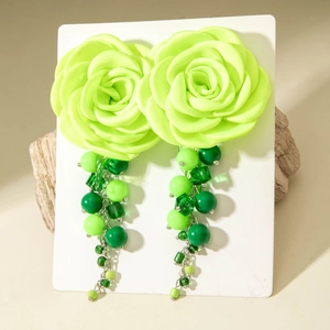 Detail of neon green fabric camellia earrings with multi-layered beaded tassels on display