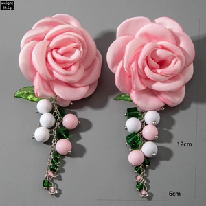 Detail of pink silk rose earrings with green acrylic leaves and beaded tassel fringe