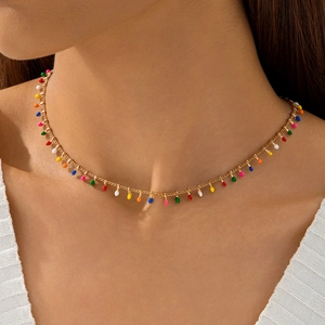 Dettaglio della collana dorata con ciondoli in smalto colorato su modella in maglia