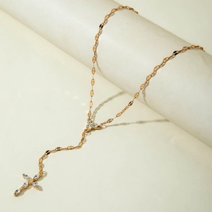 Dettaglio di una collana a Y dorata con ciondolo a croce vintage e cristalli lucidi
