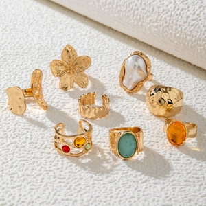 8-piece fashion ring set with gold flowers, pearls, and colorful gemstones on white texture