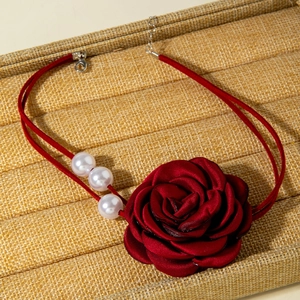 Detailed macro of a deep red fabric rose necklace with elegant white pearl accents