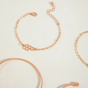 Detail of rose gold multi-layer bracelet set with hexagon pendant on a clean background