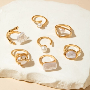 Detailed set of seven gold rings and earrings with baroque pearls and white gems on stone