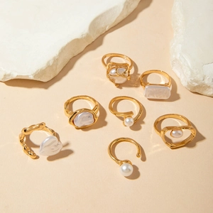 Macro detail of 7-piece gold-tone baroque pearl ring set with minimalist vintage textures
