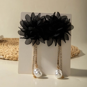 Detail of floral tassel earrings with black petals, gold chains, and faux pearls