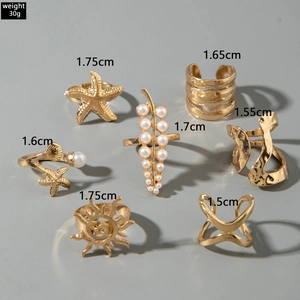 Detailed view of 7-piece gold ring set featuring starfish and pearl leaf designs