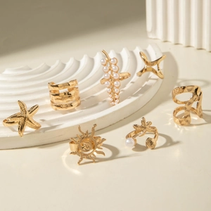7-piece gold bohemian ring set with starfish, sunray, and pearl motifs on white display