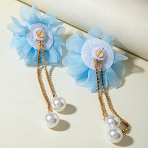 Macro detail of sky blue organza flower earrings with gold chains and pearl tassels
