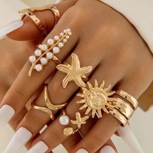 Detail view of bohemian gold ring set with star, pearl and sun motifs worn on hand