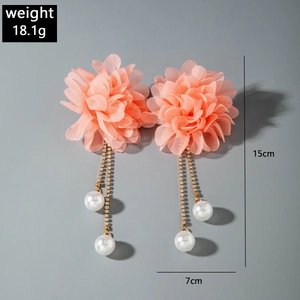 Macro shot of pink fabric flower earrings with rhinestone chains and pearls