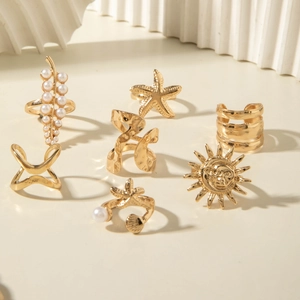 Detail of 7-piece gold ring set featuring pearl, starfish, sun, and shell motifs