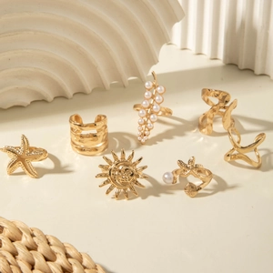 Close-up of gold alloy ring set featuring starfish and pearls on geometric white props