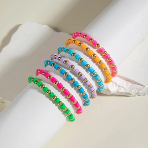 Detail of colorful bohemian Heishi clay bead bracelets set with gold accents
