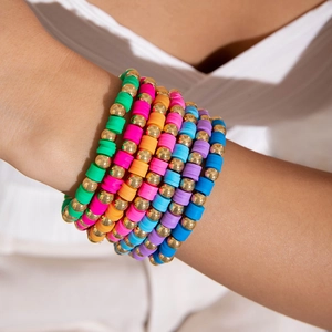 Macro shot of colorful bohemian layered elastic bracelets with heishi beads and gold accents