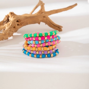 Detail of colorful Bohemian Heishi bead stretch bracelets with gold accents and wood decor