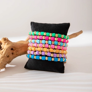 Macro detail of 7-piece rainbow heishi bead bracelets on black velvet jewelry display