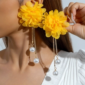 Close-up of yellow fabric flower earrings with gold chain tassels and white pearls