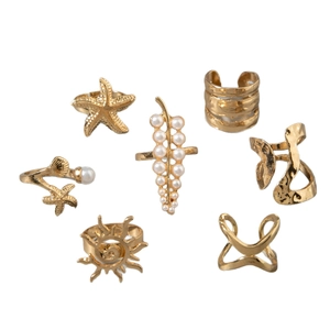 7-piece gold ring set featuring starfish, pearls, and sun motifs on white background