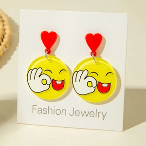 Detail of cute yellow round earrings with winking smiley faces and red heart charms