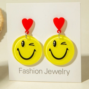 Detailed view of yellow winking smiley face earrings with red heart studs on card