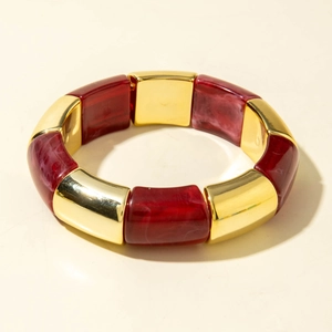 Détail d'un bracelet extensible bohème avec tubes alternés en résine rouge et métal doré