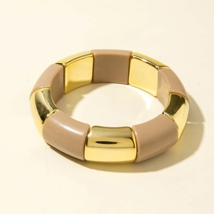 Détail d'un bracelet extensible large avec barres dorées et blocs de résine beige