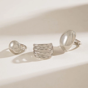 Detailed view of irregular polished silver rings set on a textured stone surface