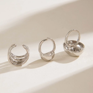 Macro detail of three minimalist silver ear cuffs with geometric and layered metal designs