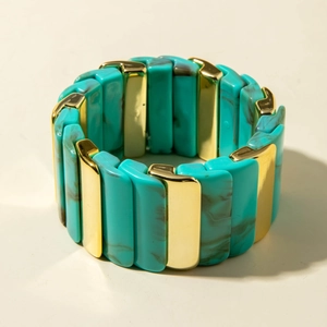 Détail de blocs de résine turquoise marbrée et de pièces en métal doré sur bracelet élastique
