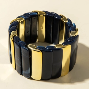 Détail d'un large bracelet en résine avec motifs marbrés bleu marine et segments dorés