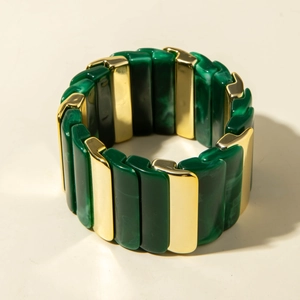 Détail du large bracelet élastique en acrylique marbré vert et pièces en métal doré poli
