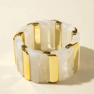 Détail d'un bracelet extensible large en acrylique marbré et métal doré poli fini